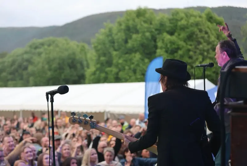 Artist på scenen sett bakfra, med publikum og fjellene foran